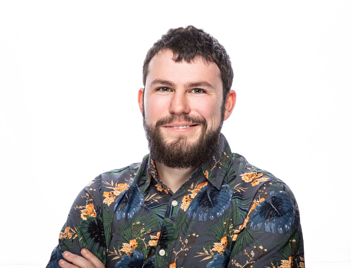 Kristian Matthews-Kennington smiling at the camera in a dark floral shirt